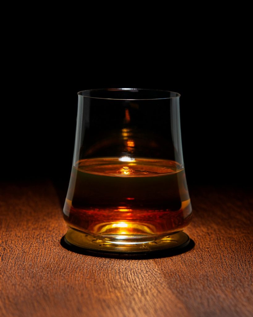 Amber whisky in a tasting glass on a wooden table