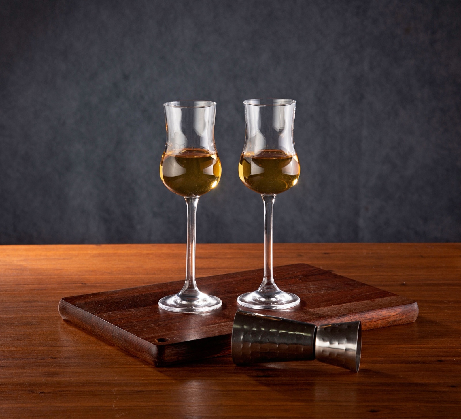 Two whisky tasting glasses on a wooden board